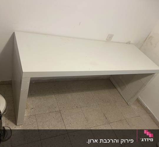 שולחן לבן בחדר ריק עם מנורה ופח אשפה